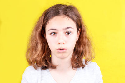 Portrait of teenage girl against yellow background