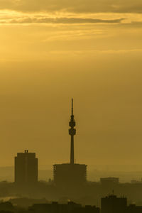 Silhouette of buildings against cloudy sky during sunset