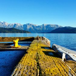 Walkway by lake against clear sky