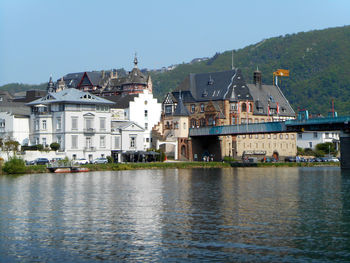 Buildings by river against clear sky