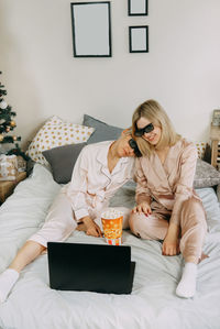 Woman using mobile phone while sitting on bed at home