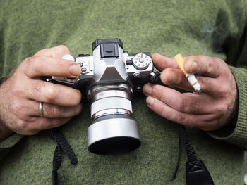 Midsection of photographer holding camera and cigarette