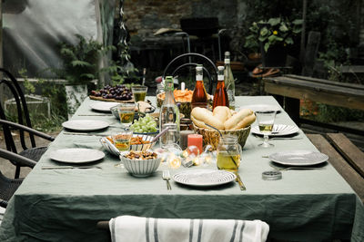 Food and drink set up with plates arranged on dining table in back yard