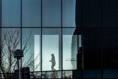 Woman at skywalk seen through glass in city