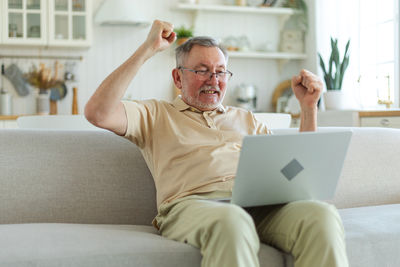 Young man using laptop while sitting on sofa at home