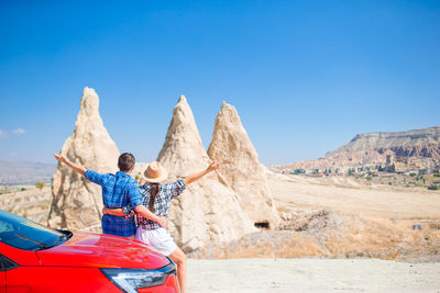 Rear view of woman standing on sand dune against clear blue sky