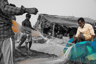 Man sitting on fishing net against boat