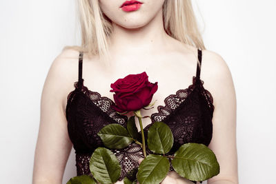 Young woman holding rose against white background