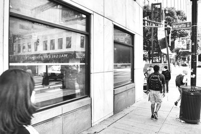 Rear view of people walking on glass window