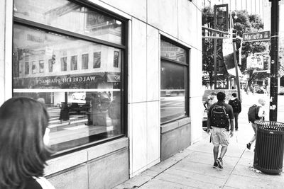 Rear view of people walking on glass window