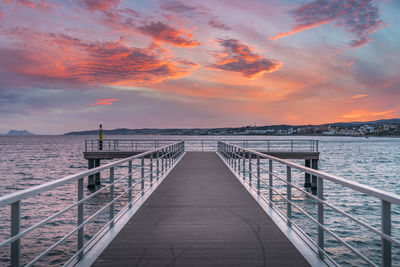 Pier over sea against sky during sunset