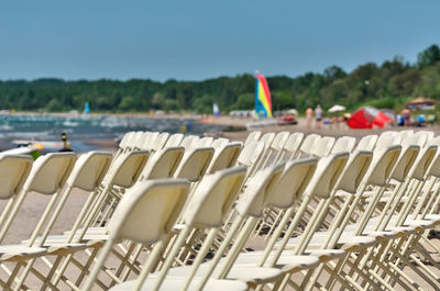 White folding chairs arranged in rows at a white sandy tropical like beach in tiny ontario canada