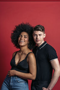 Stylish diverse girlfriend and boyfriend posing in a studio shooting with red background