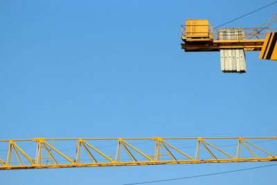 Low angle view of crane against clear blue sky