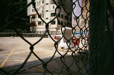 Close-up of city seen through chainlink fence