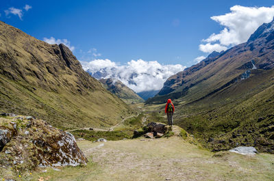 Rear view of man standing on mountain against sky