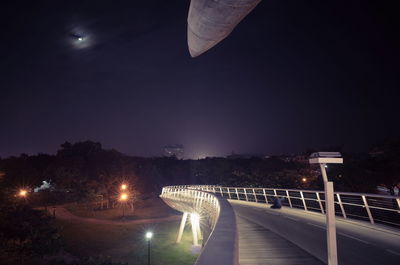 Illuminated street light against sky at night