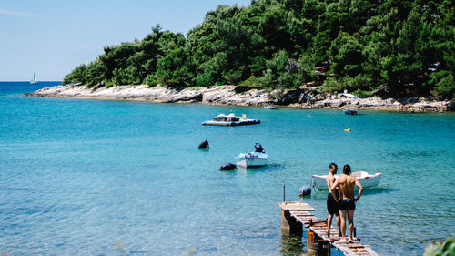 People on sea shore against trees