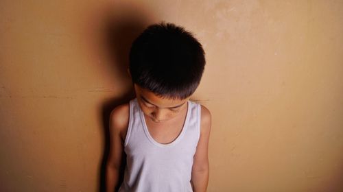 Boy standing against wall at home