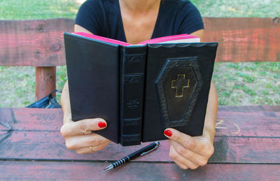 Midsection of woman reading book on table