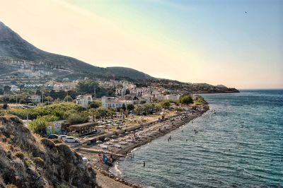 Scenic view of sea and buildings in town against sky
