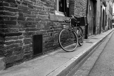 Bicycle parked on footpath against wall of building