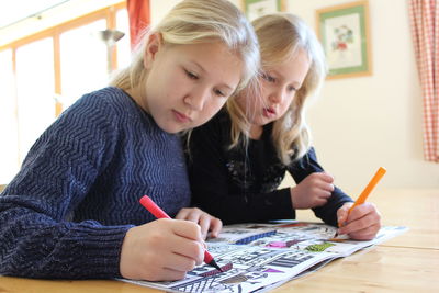Portrait of two blonde girls coloring with markers