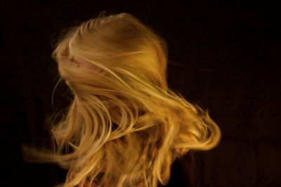 Close-up of young woman against black background