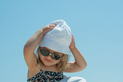 Low angle view of woman wearing sunglasses standing against clear sky