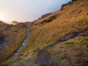 Scenic view of road by mountains against sky