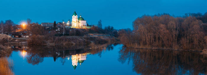 Reflection of mosque in lake against clear blue sky