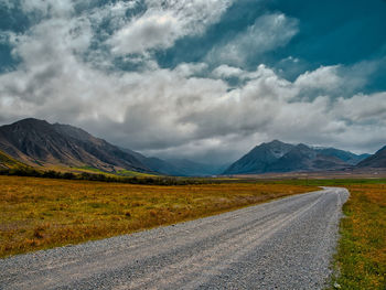 Road leading towards mountains against sky