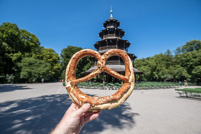 Low angle view of person holding bread against sky