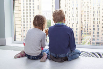 Rear view of friends sitting on window