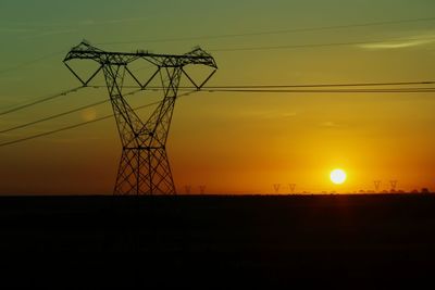 Silhouette electricity pylon against sky during sunset