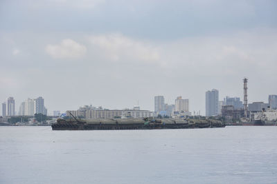 Sea by buildings against sky in city