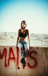 Woman sitting on a graffitied wall