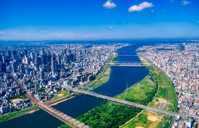 High angle view of city by sea against blue sky