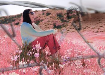 Side view of mid adult woman wearing sunglasses siting on grassy field in park