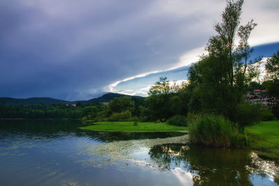 Scenic view of lake by trees against sky