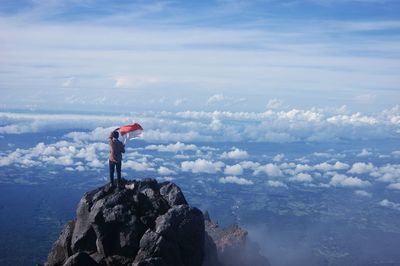 Man standing on rock by mountains against sky