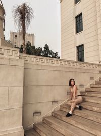 Full length of woman sitting on staircase in city