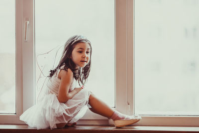 Girl looking through window at home