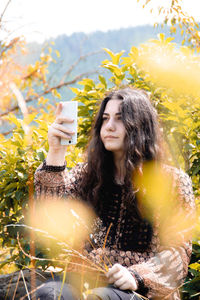 Portrait of smiling young woman holding smart phone outdoors