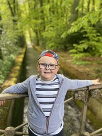 Portrait of boy wearing eyeglasses standing against trees