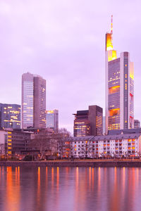 Modern buildings by river against sky in city