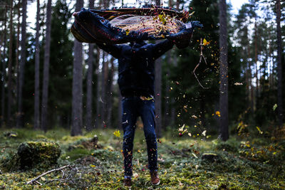 View of man shaking sleeping bag in forest