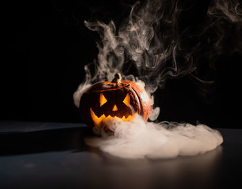 Close-up of burning candle against black background