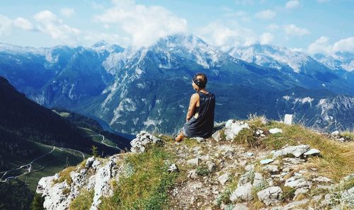 Man sitting on rock against mountains