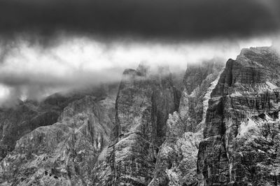 Low angle view of rocky mountains at tre cime di lavaredo during foggy weather